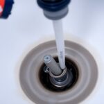 Plumber unclogging a bathroom sink drain.